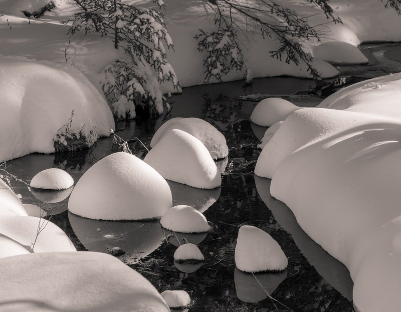 Rounded caps of snow sit above a narrow dark stream.