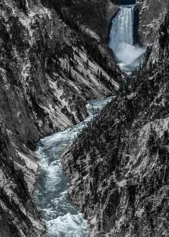 A tall waterfall pouring into a narrow rocky canyon.